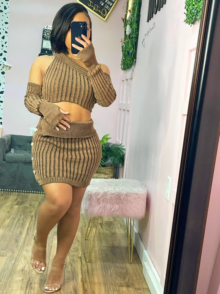 Person wearing a brown ribbed outfit taking a mirror selfie in a room with pink walls and decor.
