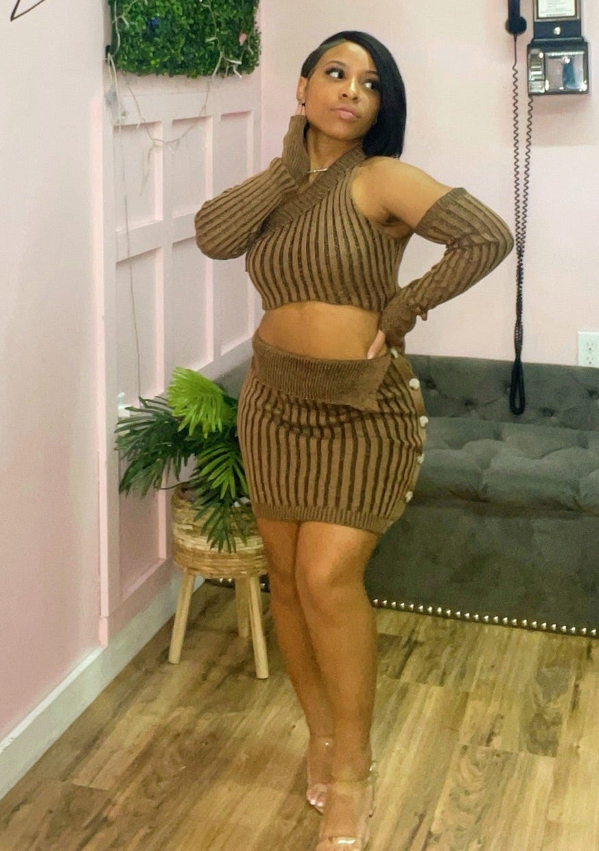 Woman in a brown ribbed outfit posing in a boutique setting.